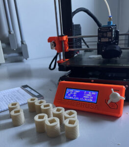 A sample of the 45 bioplastic deck plugs beside the 3D printer that Pegram and Su brought with them on the excursion.